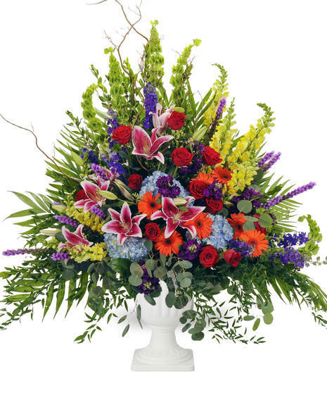 An arrangement of bright roses, hydrangeas, snapdragons, bells of Ireland, lilies, and gerbera daisies, and other greenery. Displayed against a white background.