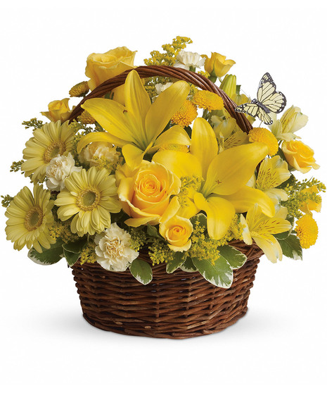 Bright yellow flowers and butterfly decoration in a wicker handbasket.