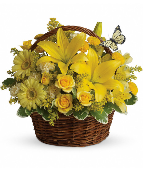 Bright yellow flowers and butterfly decoration in a wicker handbasket.
