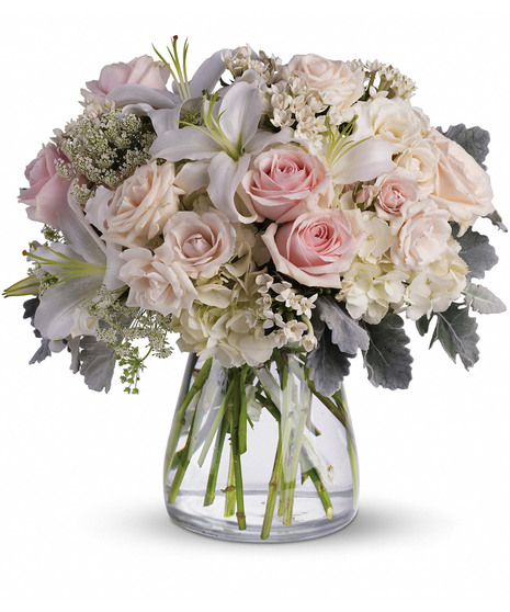 Pastel pink and white roses in a clear glass vase