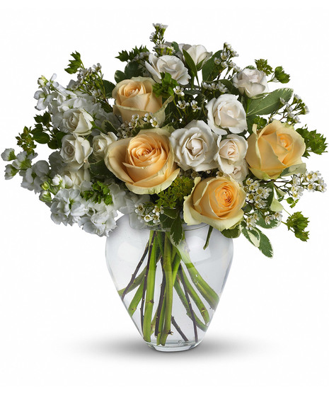 White and yellow flowers and greenery in a clear glass vase
