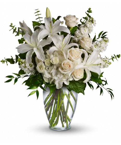 White and peach blossoms in a clear glass vase with greenery.