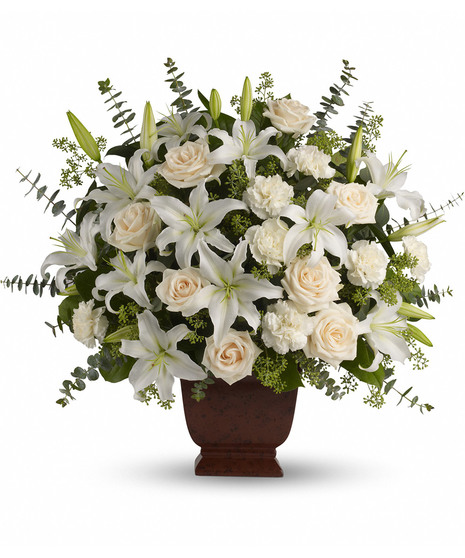 Elegant arrangement of white and creme flowers and greenery presented in an urn