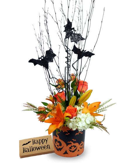 A Halloween floral arrangement in a ceramic pumpkin container, featuring orange lilies, white hydrangeas, orange roses, and alstroemeria. 