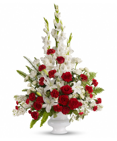 White sympathy urn filled with red and white flowers and greenery