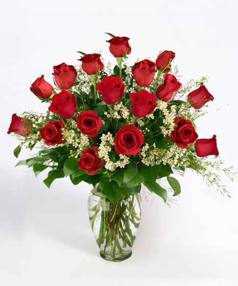One dozen roses and greenery in a clear glass vase