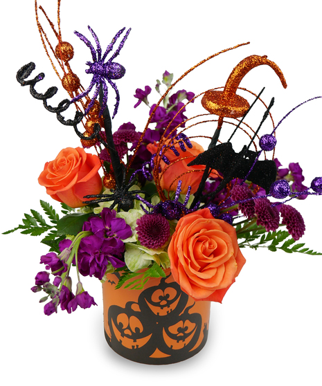 spooky orange and purple flowers and ornaments in an orange pumpkin container