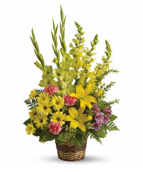 Bright yellow, green, pink and purple flowers presented in a sympathy basket