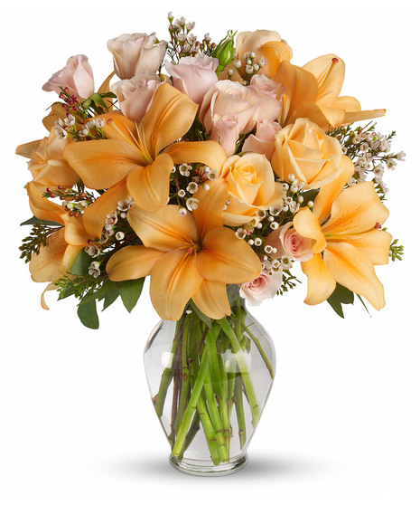 A collection of peach and orange flowers in a clear glass vase