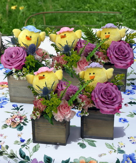 Set of three Easter floral arrangements featuring plush yellow chicks surrounded by pink roses and spring flowers arranged in rustic wooden cube containers.