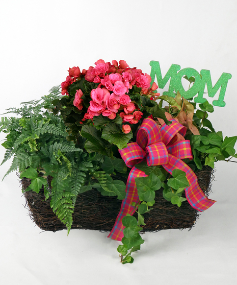 Image showcases a large European garden-style garden arranged in a rectangle grapevine basket including a mix of bright blooming plants and long-lasting green foliage plants
