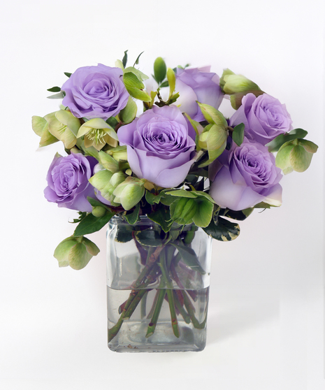 Compact rose arrangement featuring premium roses in a glass cube vase accented with seasonal greenery.