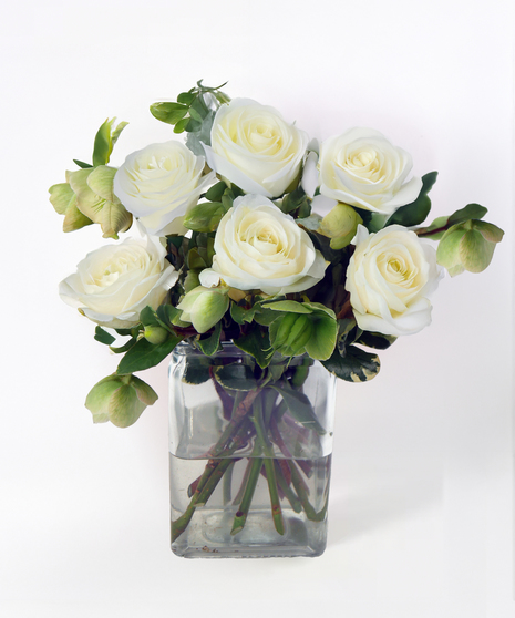 Compact rose arrangement featuring premium roses in a glass cube vase accented with seasonal greenery.