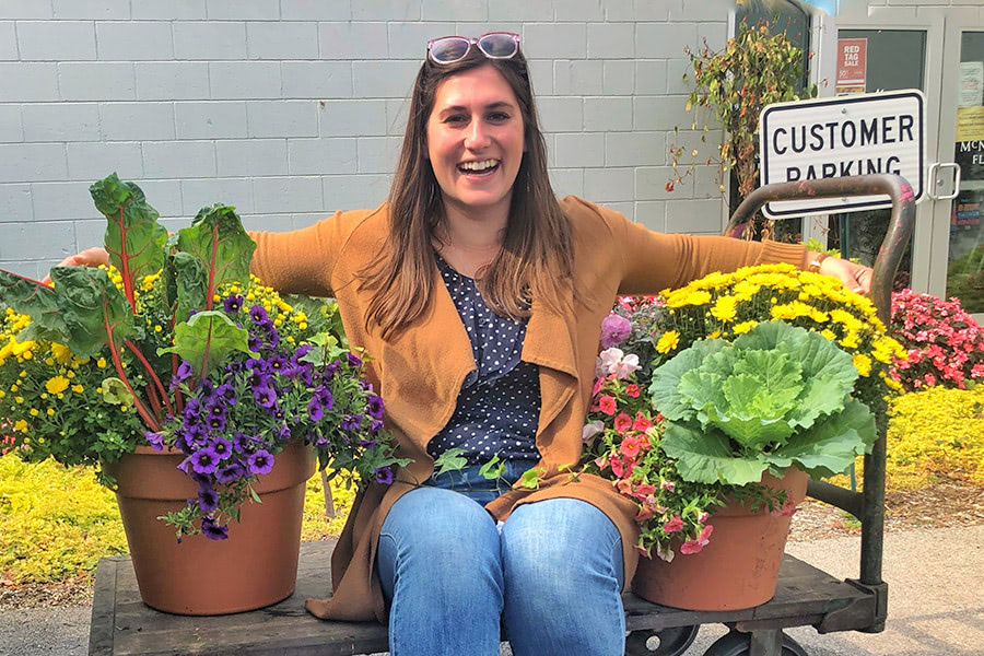 Erin Davidson, our Marketing Coordinator, wraps her arms around a pair of potted plants